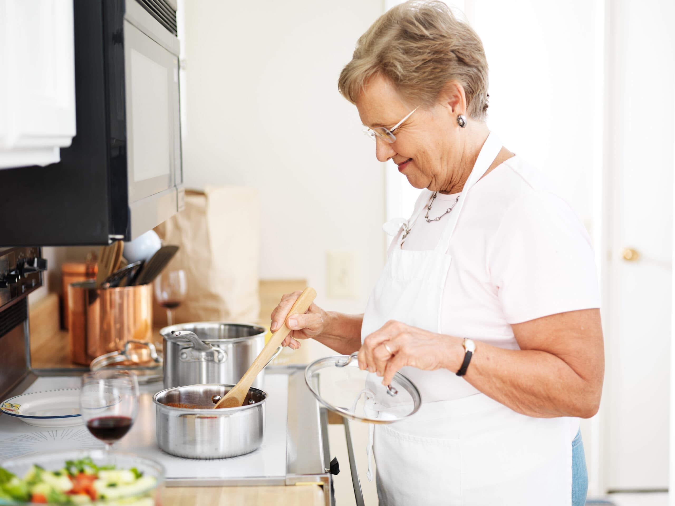 elderly woman cooking a meal on the stove