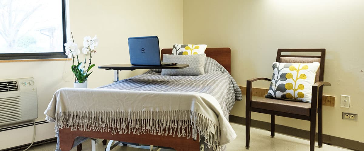 Comfortable resident room with bed, nightstand, and personal furnishings at Embassy Oaks