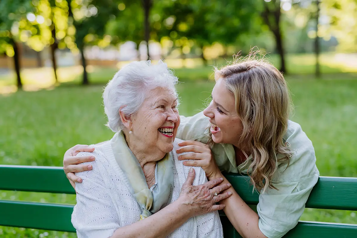 Caregiver helping an elderly woman with activities at an adult daycare program