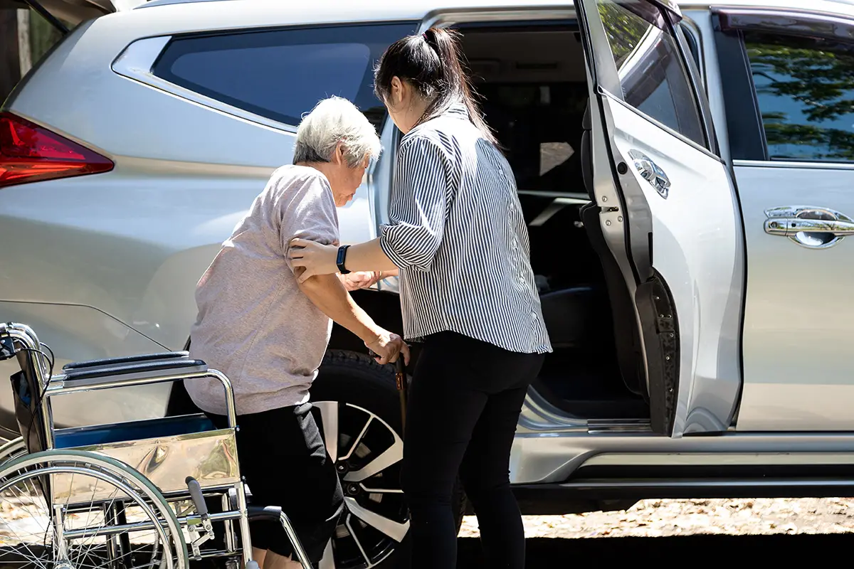 Senior being assisted into a transportation vehicle at an adult daycare program