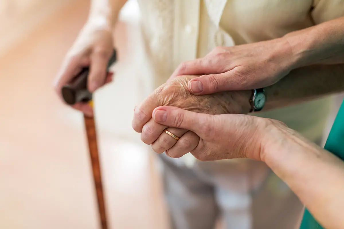 Caregiver assisting an elderly woman with mobility in an assisted living community