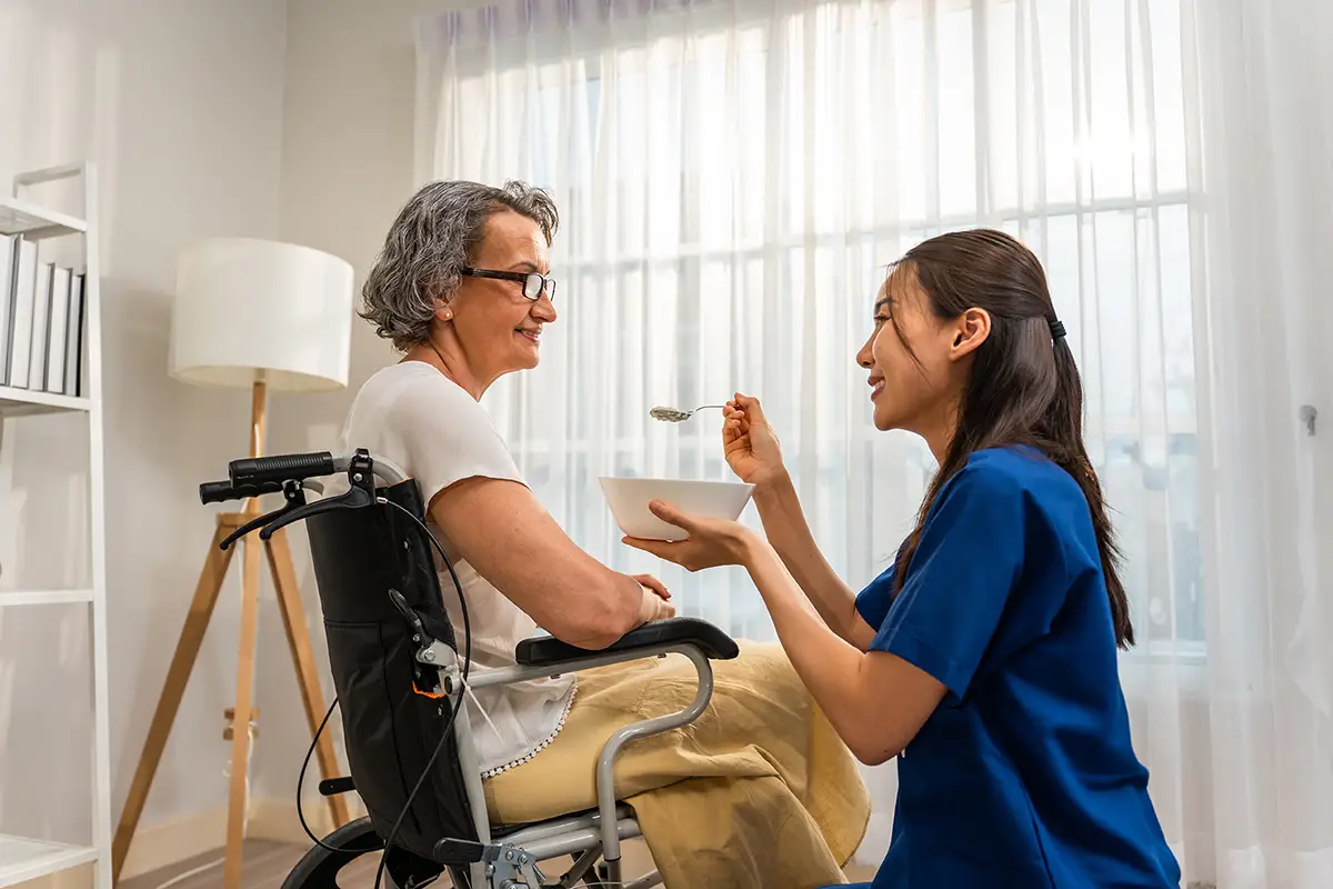 Caregiver providing daily living assistance to a hospice care patient