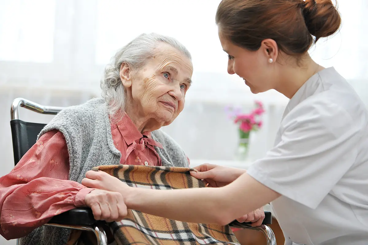 Compassionate caregiver comforting an elderly woman during hospice care