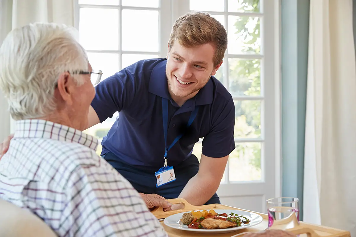 Caregiver helping an elderly resident enjoy a nutritious meal in long-term care