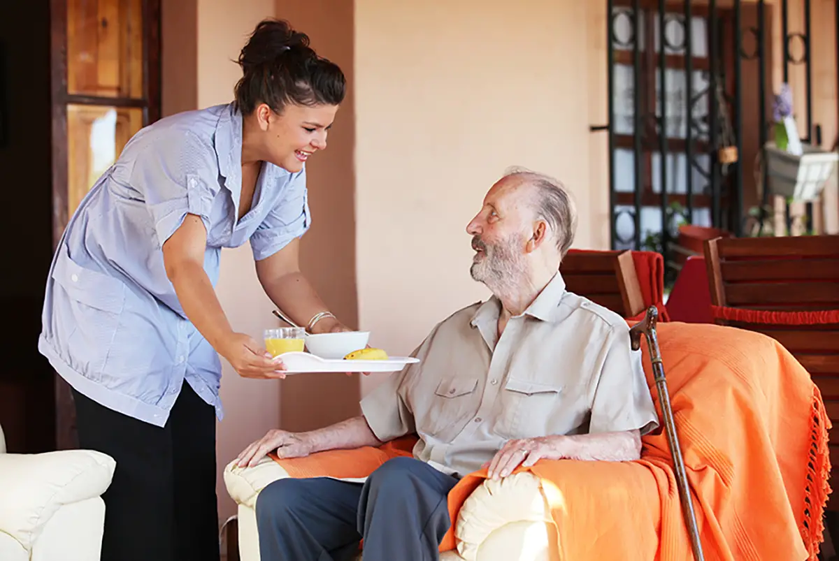 Caregiver helping a memory care resident with dietary support and meal assistance