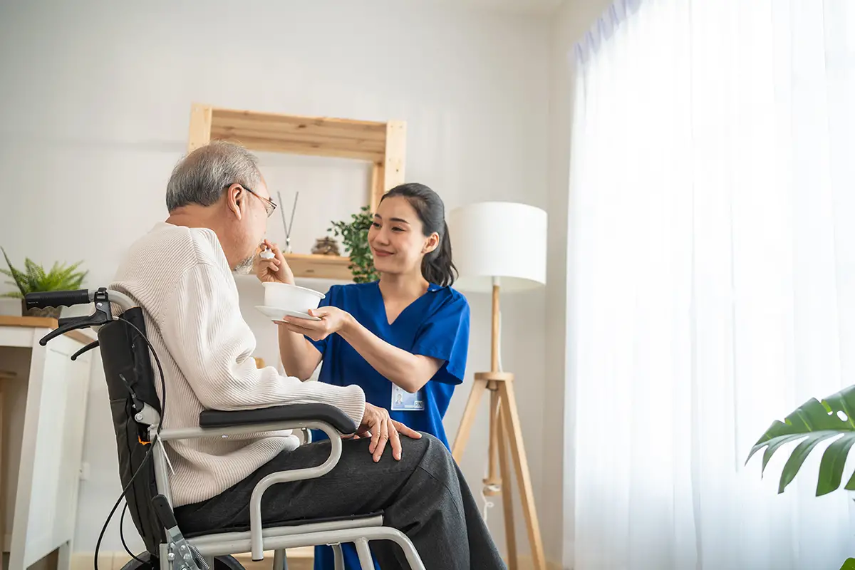 Caregiver assisting an elderly resident with eating and feeding during nutrition care