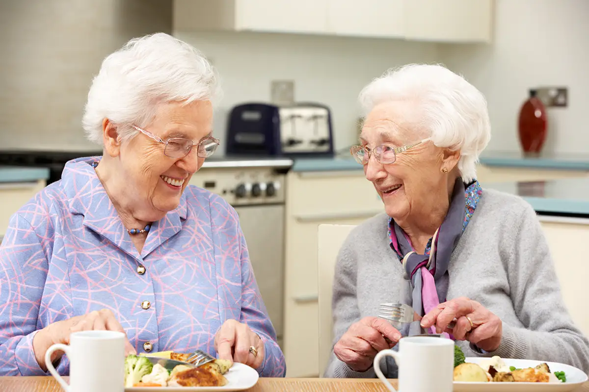 Smiling elderly women enjoying a nutritious meal together in a care setting