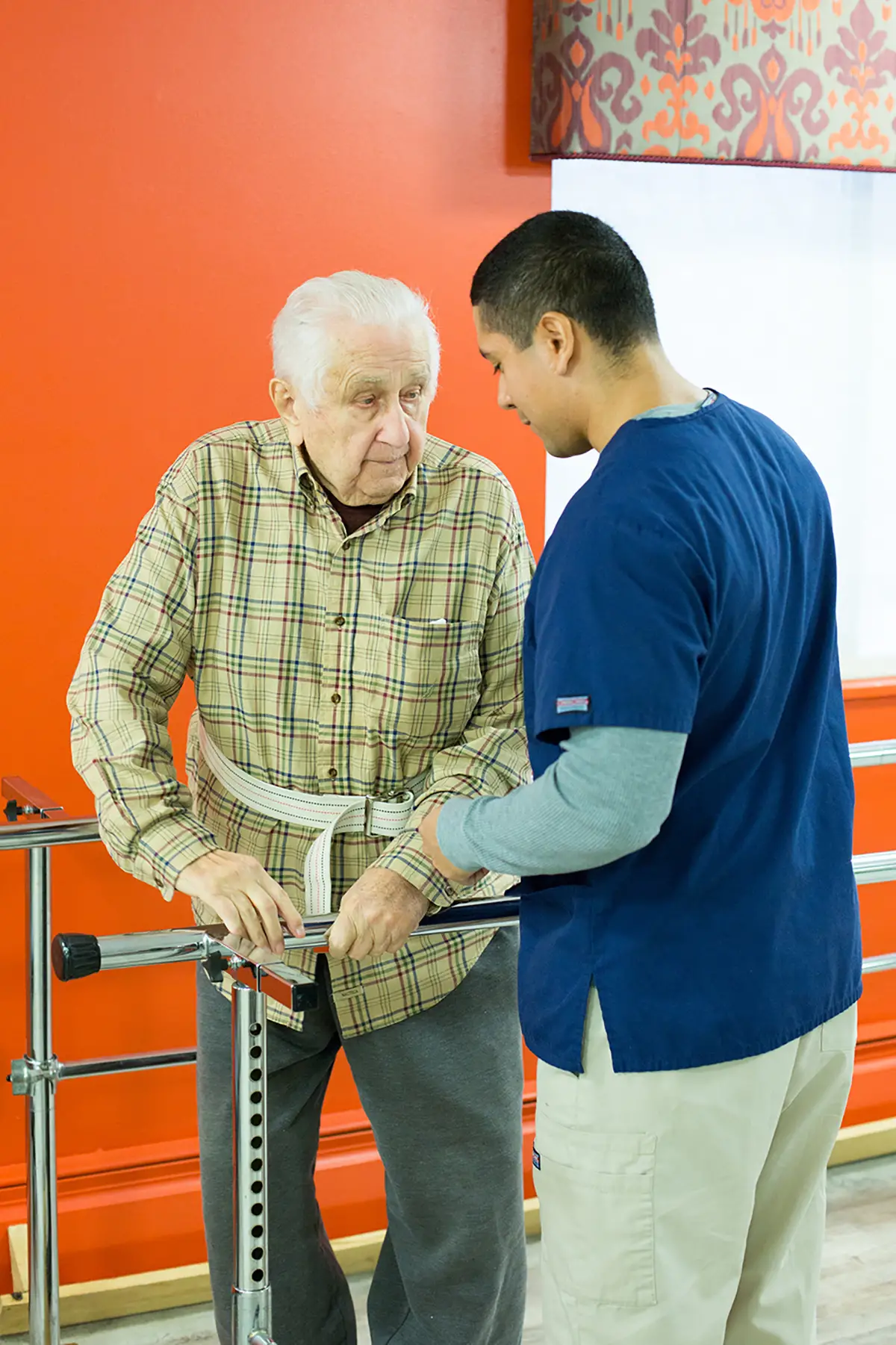 Elderly man using a walker with caregiver support for orthopedic fall prevention