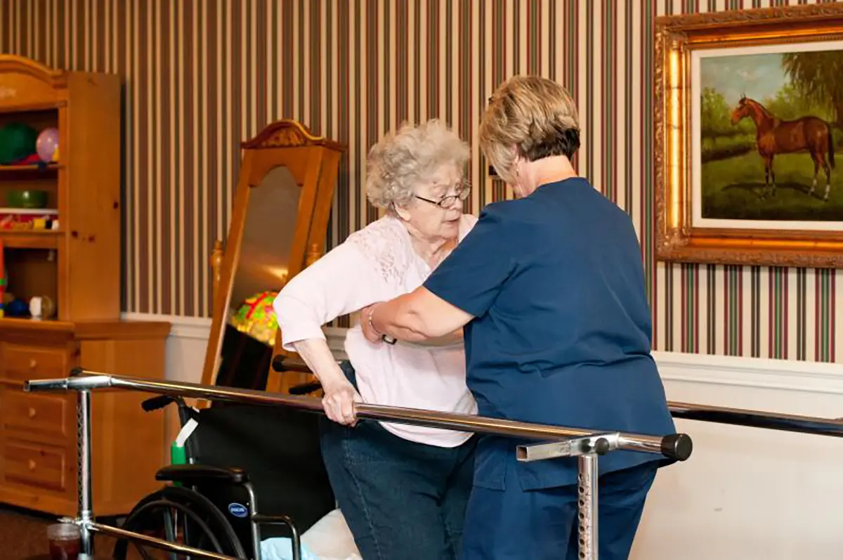 Nurse assisting an elderly patient with rehabilitation therapy exercises