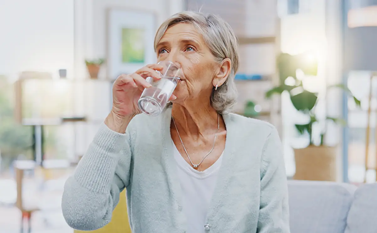 Elderly woman drinking water as part of renal care fluid management