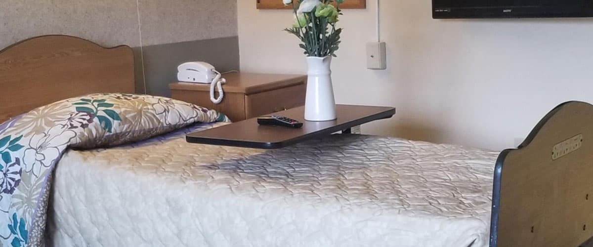 Private bedroom with comfortable bed and blue decorative bedding at Woodview facility